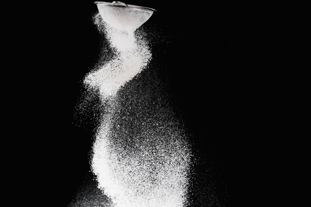 sieve with falling flour isolated on blackの写真素材