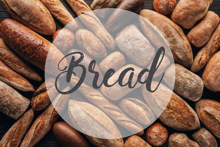 top view of arranged loafs of bread on wooden surface and bread lettering