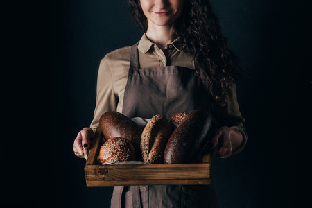 cropped shot of smiling woman holding wooden box with loafs of bread in handsの写真素材