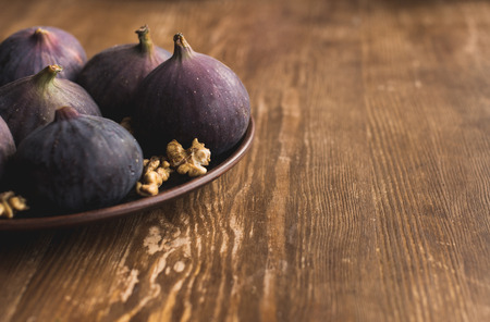 Bowl with raw figs and skinless walnuts on wooden table