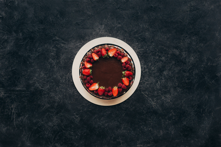 Top view of chocolate cake with strawberries and raspberries on gray surfaceの写真素材