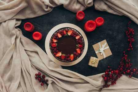 Top view of chocolate cake with berries and candles on a gray surfaceの写真素材