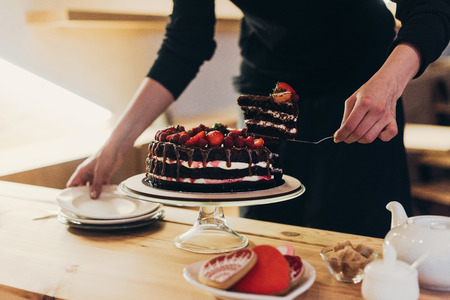 Cropped image of woman taking piece of appetizing cakeの写真素材