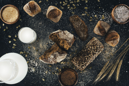 top view of organic homemade bread and milk in glass and jug on blackの写真素材