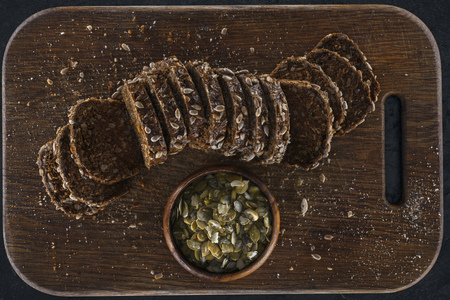 top view of sliced bread with pumpkin seeds on wooden cutting board