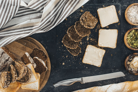 top view of toasts with butter and multigrain bread with knife on black の写真素材
