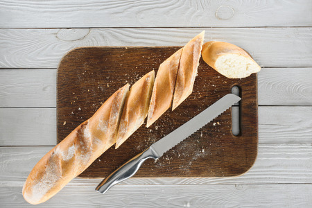 top view of sliced homemade baguette and knife on wooden cutting board の写真素材