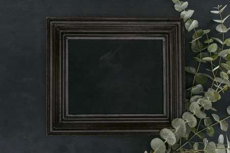 top view of vintage wooden frame with eucalyptus branches over black backgroundの写真素材