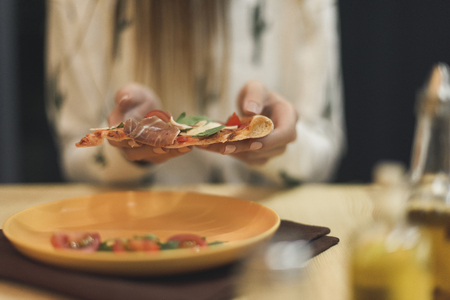 partial view of woman holding piece of italian pizza in handsの写真素材
