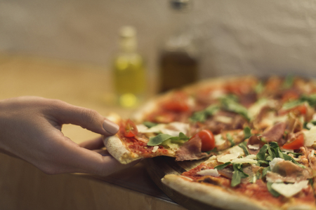 cropped shot of woman taking piece of italian pizzaの写真素材