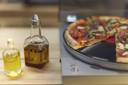 close up view of types of oil in bottles and italian pizza on vinyl record player