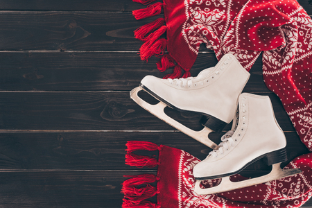 top view of pair of white skates and red scarf on wooden tableの写真素材