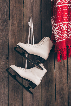 pair of white skates and red scarf hanging on wooden wallの写真素材
