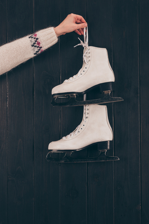 cropped image of woman holding pair of white skates on gray の写真素材