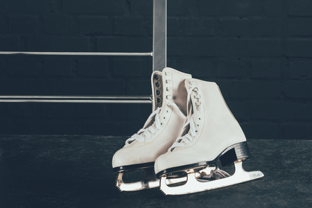 pair of white figure skates on gray floorの写真素材