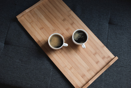 top view of two cups of coffee on wooden tray on sofa の写真素材