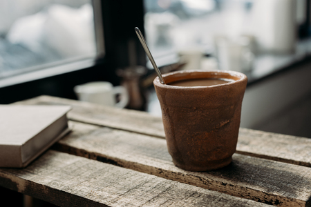  Clay cup of coffee with milk on wooden rustic table with bookの写真素材
