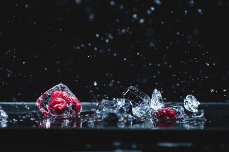 close-up view of ripe frozen berries in ice crystals melting on blackの写真素材