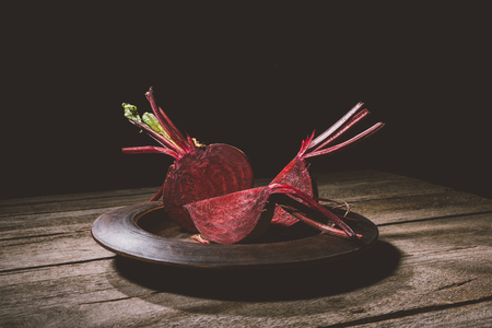Close-up view of fresh ripe beet in plate on wooden tableの写真素材