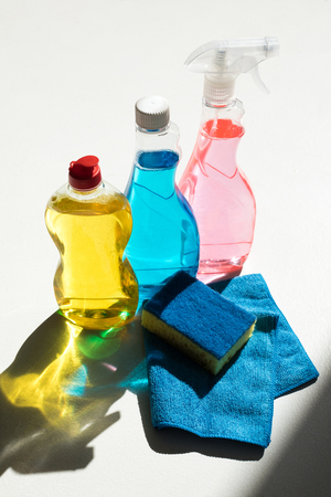 close-up view of plastic bottles with colorful cleaning products, sponge and rag on whiteの写真素材