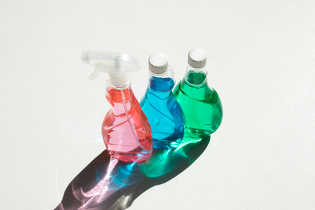 high angle view of plastic bottles with colorful cleaning fluids on white の写真素材
