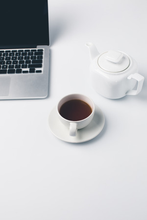 modern workplace with cup of tea and laptopの写真素材