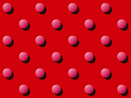 close-up view of pattern made from round pink medical tablets on redの写真素材