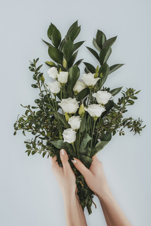 cropped image of female hands holding bouquet with eustoma flowers isolated on greyの写真素材
