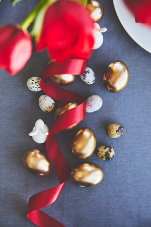 top view of golden easter eggs and ribbon on tableclothの写真素材