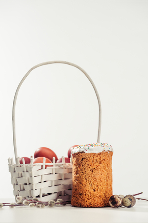 decorative basket with painted chicken eggs, easter cake, quail eggs and catkins on greyの写真素材