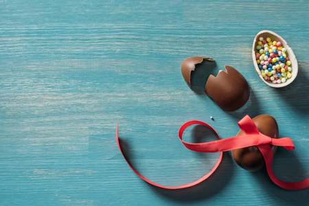 top view of broken chocolate easter eggs on turquoise tableの写真素材