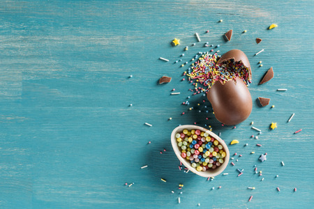 top view of broken chocolate easter eggs on wooden turquoise tableの写真素材