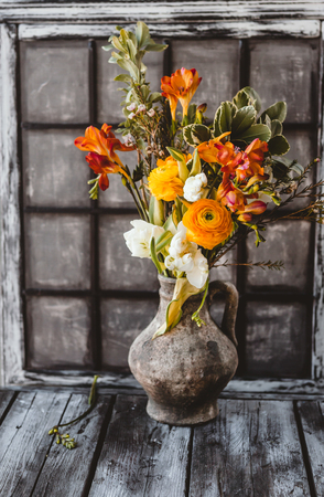 Ceramic jug with spring flowers on wooden tableの写真素材