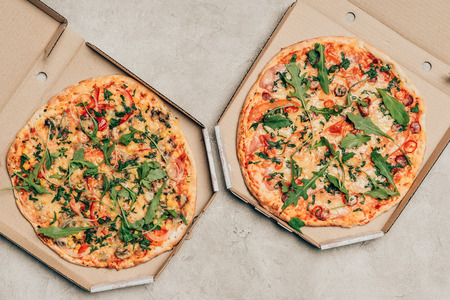 Hot Italian pizzas with arugula in cardboard boxes on light backgroundの写真素材