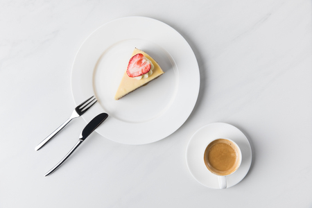 Cheesecake with strawberry on top and cup of coffeeの写真素材