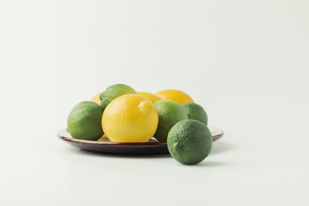 Lemons and limes on plate isolated on white background
