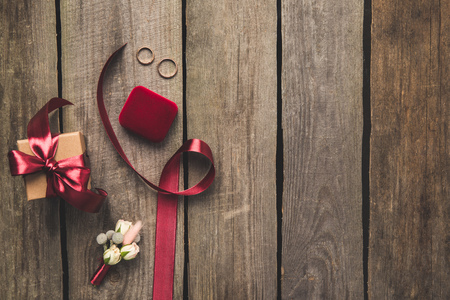 flat lay with ribbon, wedding rings, corsage and gift on wooden tabletopの写真素材