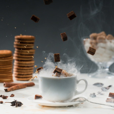 Close-up of brown sugar cubes falling into coffee cup with splashesの写真素材