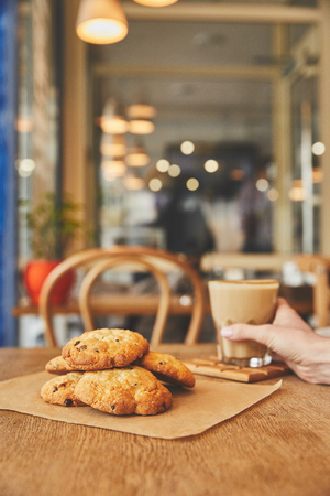 Hand holding glass with coffee by cookiesの写真素材