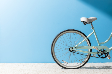 back wheel of bicycle standing on carpet in front of blue wallの写真素材