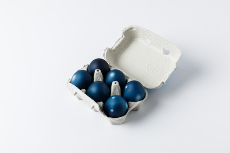 six blue painted easter eggs in egg tray on whiteの写真素材