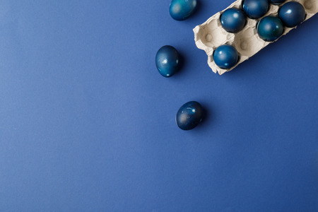 top view of blue painted easter eggs and egg tray on blue surfaceの写真素材