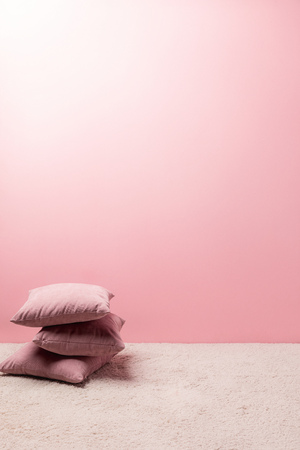 pillows on carpet in front of pink wallの写真素材