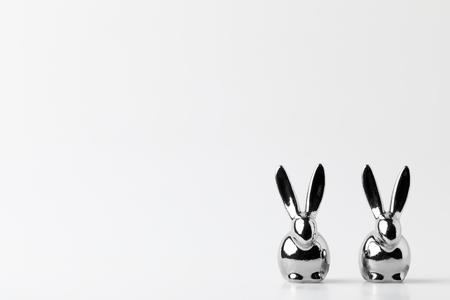 two statuettes of silver easter bunnies on whiteの写真素材