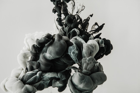 close up view of mixing of light gray and black paints splashes in water isolated on grayの写真素材