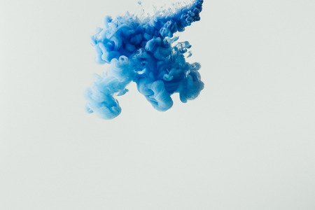 close up shot of bright blue paint splash in water isolated on grayの写真素材