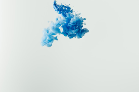 close up shot of bright blue paint splash in water isolated on grayの写真素材