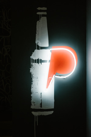 illuminated beer bottle symbol on dark wall in pubの写真素材