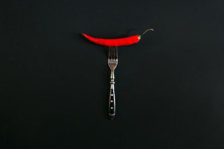 red hot chili pepper on fork on blackの写真素材