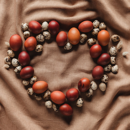 top view of heart shaped frame made of easter eggs and quail eggs on linen tableclothの写真素材